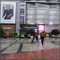 Luxury storefronts and pedestrians around the plaza near Liberation Monument during the day