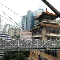 View from a small connecting bridge revealing Chongqing’s dense, multi-level cityscape with buildings rising and descending along steep terrain