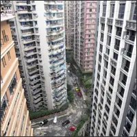 Looking down between tall residential buildings in Chongqing, showing streets and structures far below