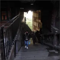 People walking up a steep staircase inside Hongyadong with light filtering in from above