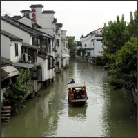 Canal scene near Hanshan Temple with traditional houses and passing boat