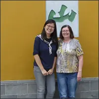 Two women standing together in front of a wall at Hanshan Temple