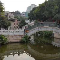 Stone bridge crossing a narrow canal in a quiet Guangzhou neighborhood.