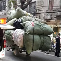 Cargo tricycle carrying an oversized load through a Guangzhou street.