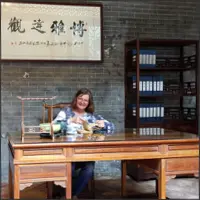 Seated at a traditional Qing Dynasty-style desk in Yuyin Shanfang Garden.