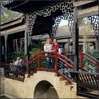 Two people standing on a red bridge in Yuyin Shanfang Garden.