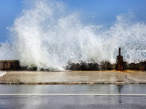 Waves breaking against the seawall with damaged concrete along the Prachuap waterfront