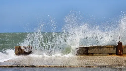 Waves breaking against the seawall with damaged concrete along the Prachuap waterfront