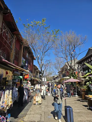 Busy Kunming street lined with colorful merchandise under a deep blue sky.